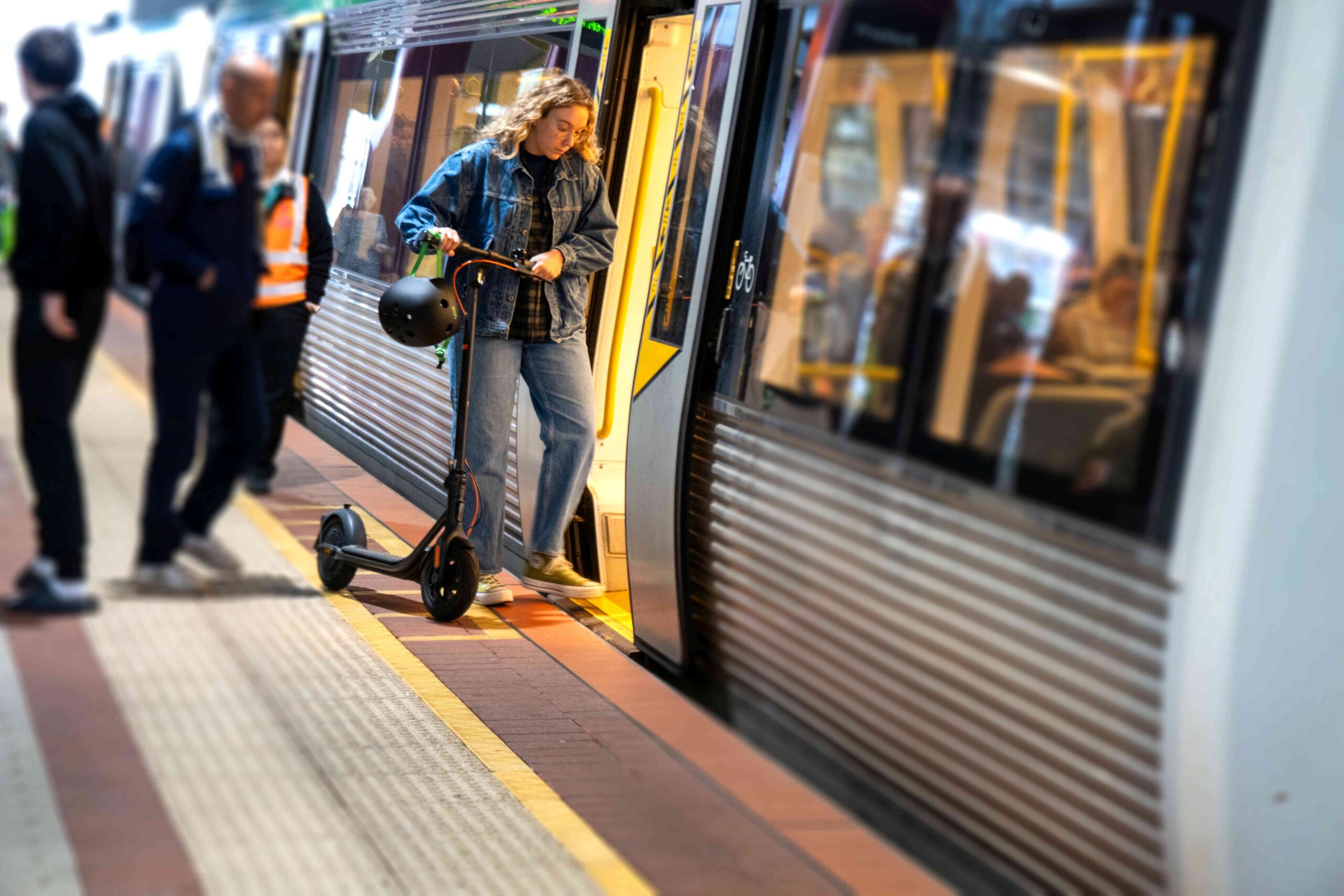 Woman stepping into a train carriage with an e-scooter.